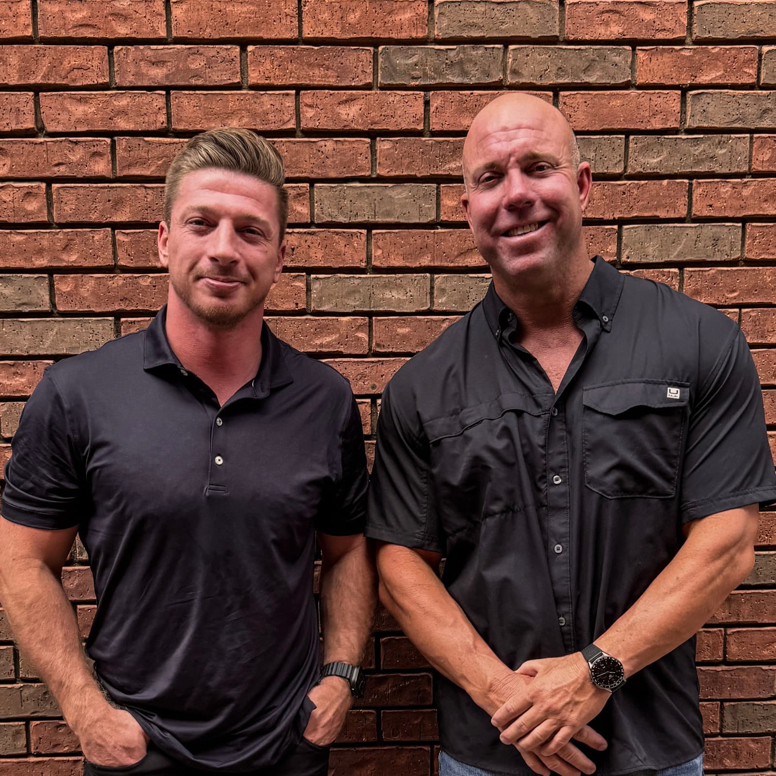 Brett and Matt standing in front of a brick wall